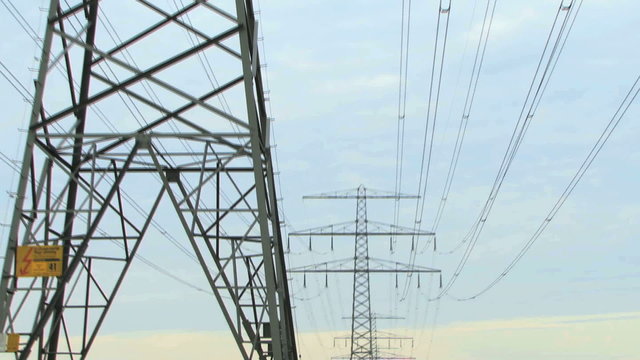 Zoom out on electricy pylon and powercables at sunset