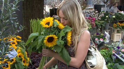Female buying flowers on flower market and smelling them