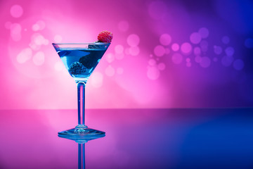 Colorful cocktails with berries, light effects background