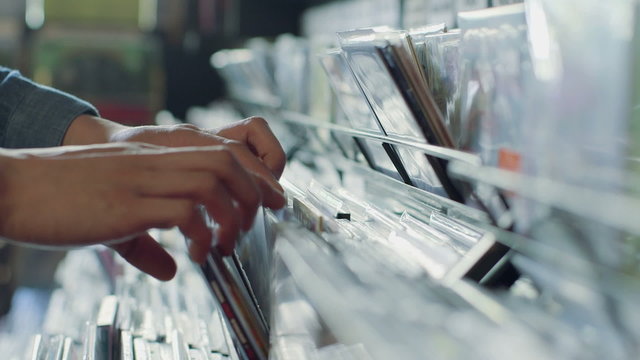 CU A Young Man's fingers flick through a rack of vintage records