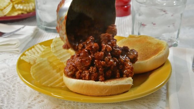 Sloppy joe hamburger mix being ladled onto a bun