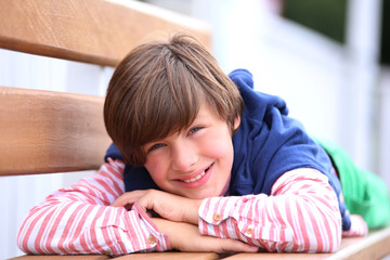 Young boy relaxing on bench in park