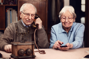 Senior couple with old telephone and smartphone