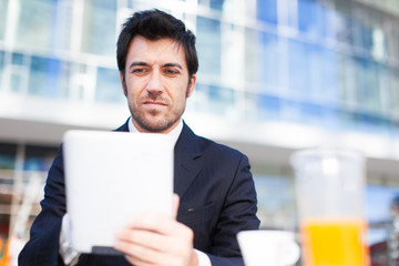 Businessman using his tablet while having breakfast