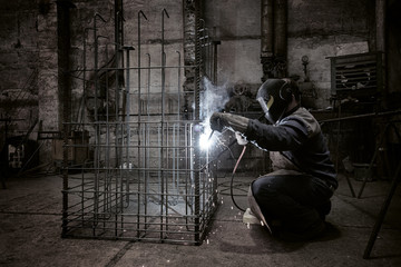 Welder with protective mask welding reinforcement bars - obrazy, fototapety, plakaty