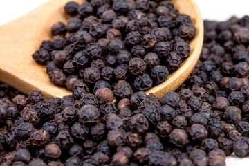 closeup black pepper in wooden spoon on fabric
