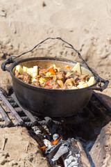 meat with potatoes in a cauldron on fire
