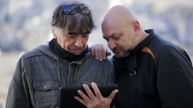 two men surfing the internet with a tablet computer