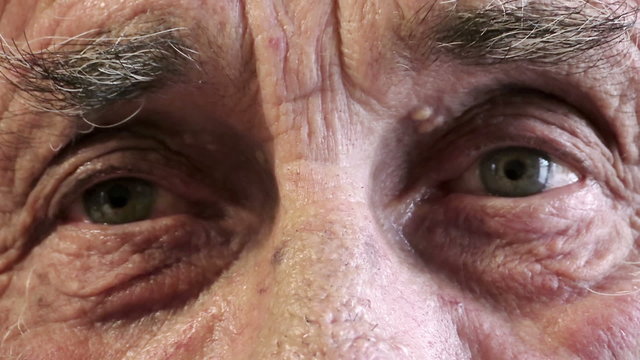 old man opens and closes his eyes in front of the camera