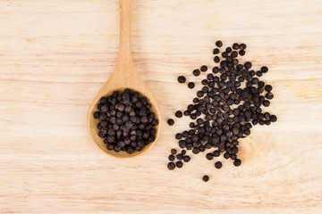 Closeup dried black pepper on wooden plate