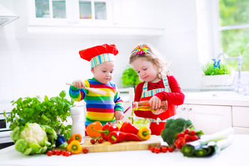Kids cooking vegetables in a white kitchen
