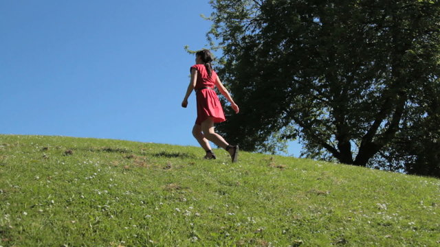 Female dancing and jumping on hill in park