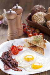 Fried egg and bacon on a plate with spices and vegetables