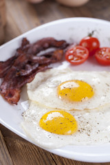 Fried egg and bacon on a plate with spices and vegetables