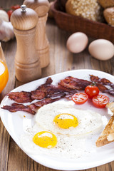 Fried egg and bacon on a plate with spices and vegetables