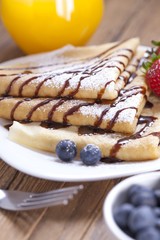 Delicious sweet French pancakes on a plate with fresh fruits