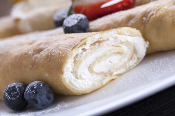 Delicious sweet rolled pancakes on a plate with fresh fruits