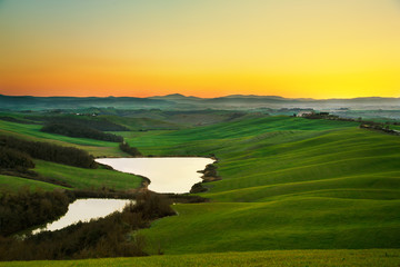 Tuscany, rural landscape on sunset, Italy. Lake and green fields