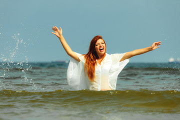 Vacation. Girl splashing water having fun on the sea.