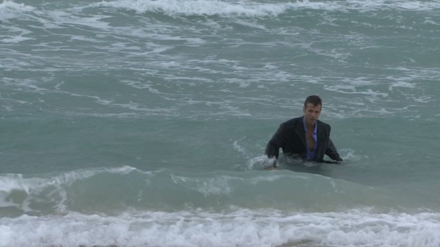 Male walking out of the ocean in suit