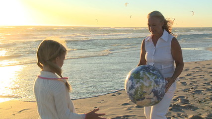 MS OF A GRANDMOTHER AND GRANDDAUGHTER THROWING A BEACH BALL - Powered by Adobe