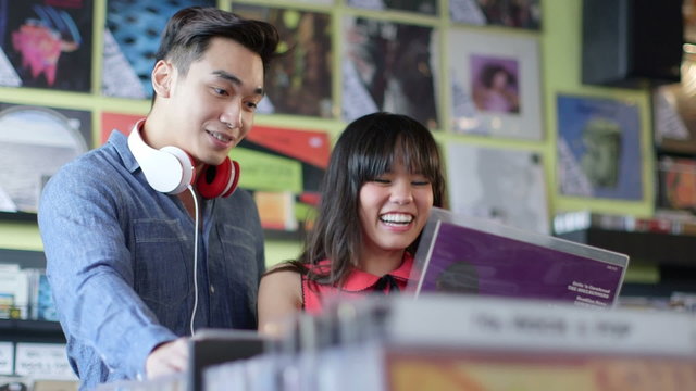 A Young Woman and Young Man happily flick through vintage records together