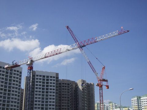 Modern buildings under construction and cranes under a blue sky
