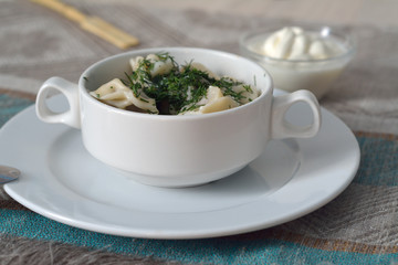 Pelmeni in a bowl with sour cream