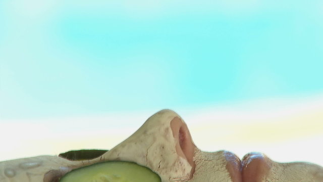 BCU PAN OF A WOMAN WEARING A FACE MASK WITH CUCUMBER SLICES ON HER EYES
