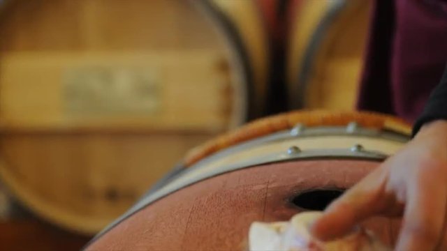 Winemaker in cellar making wine test.