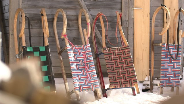 Arranged sledges in snow outside wooden house