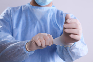 Male doctor putting on disposable gloves