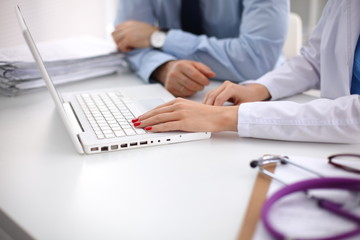 Male doctor using a laptop, sitting at his desk