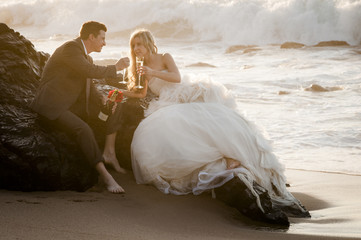 Fototapeta na wymiar Young happy bridal couple on beach rocks at sunrise