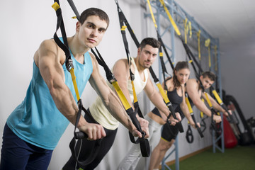 People at gym doing trx rope exercises