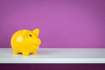 A happy yellow piggy bank on a shelf with copy space background