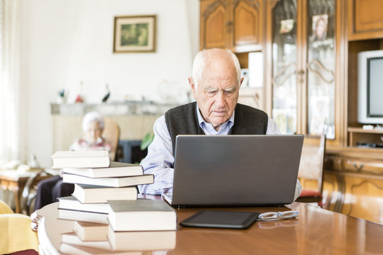 Senior man looking for information in books and internet