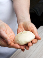 Woman's hands knead dough.