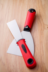 Two metal spatula with a red handle on wooden background