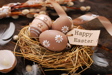 easter eggs and paper tag with greetings in nest