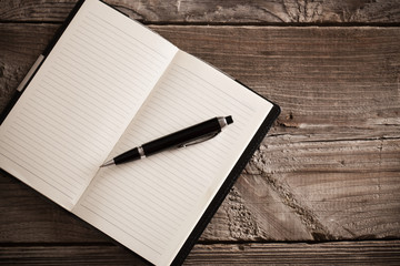 notebook with pen  on old  wooden table