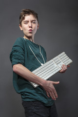 teenage boy using a computer keyboard like a guitar, isolated on