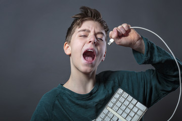 singing teenage boy with computer keyboard and gray background f