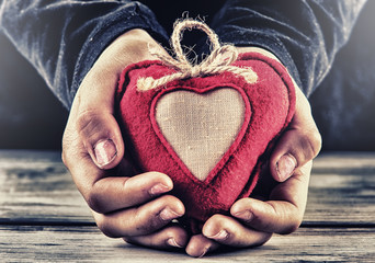 Red canvas valentine heart in the hands of a child.