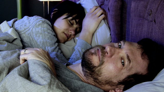 Man desperate crying in bed while girlfriend is sleeping