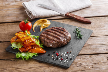 burger grill with vegetables and sauce on a wooden surface