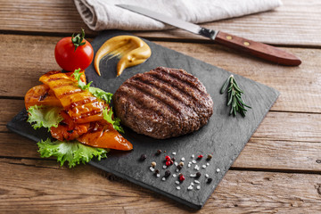 burger grill with vegetables and sauce on a wooden surface
