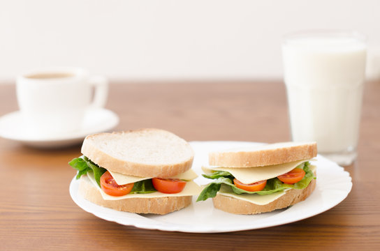 Sandwiches on a plate and glass of milk, cup of coffee