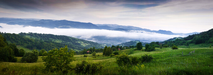 Summer landscape with a mountain village in the mist