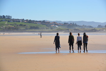 grupo de chicas paseando por la playa de oyambre